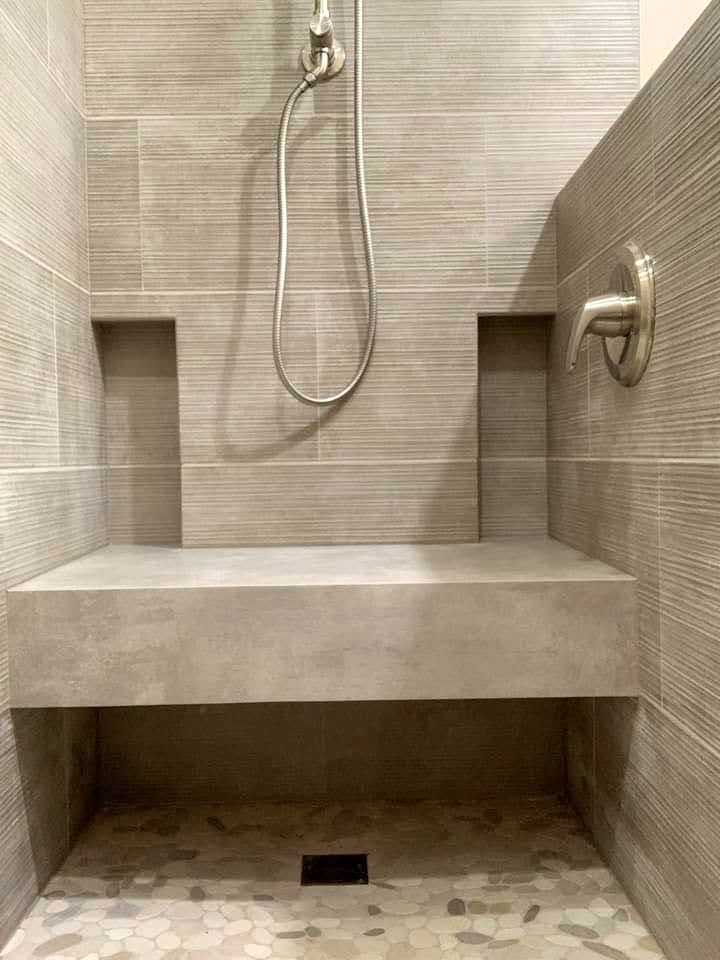 A shower with a bench and a shower head.