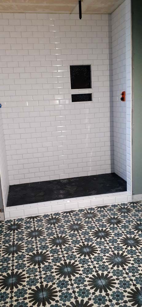 A bathroom with a walk in shower and a tiled floor.