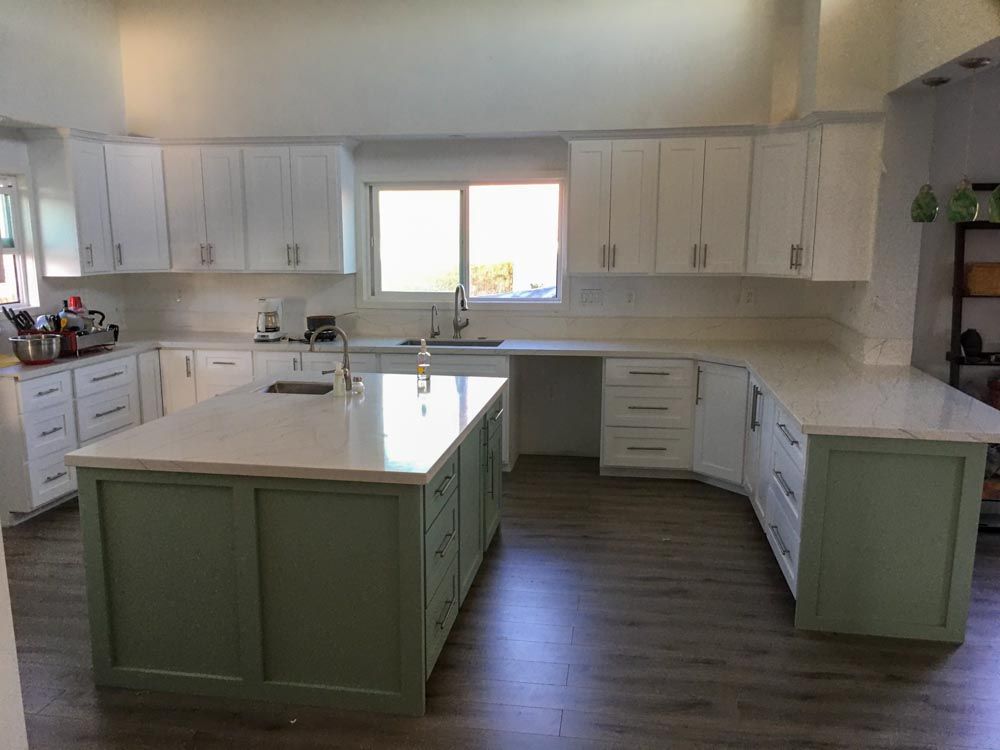 A kitchen with white cabinets and a large island in the middle.