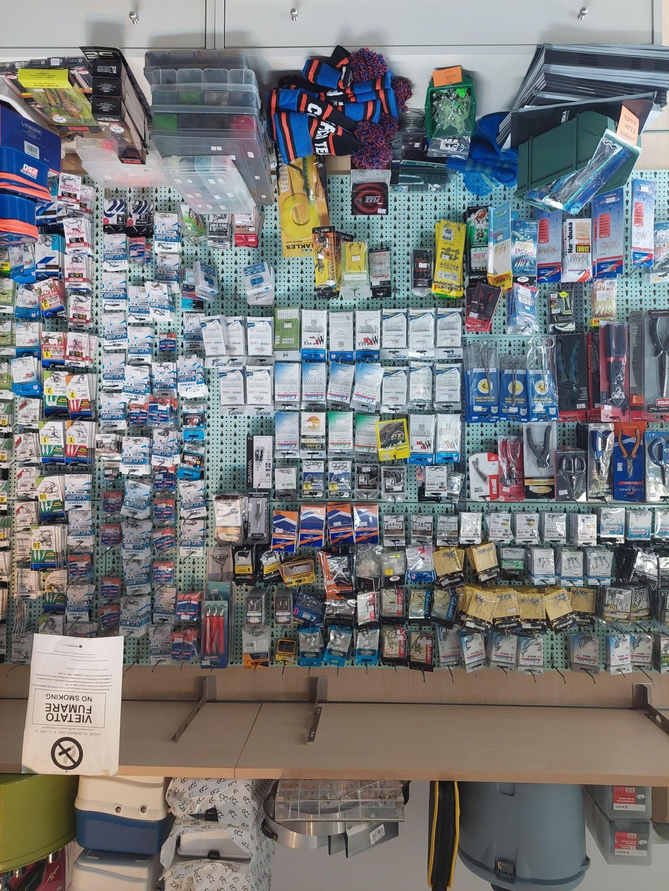 Espositore da negozio di attrezzatura da pesca con numerosi piccoli articoli confezionati. Gli scaffali sono in basso.