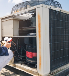 HVAC technician inspecting an air conditioning unit on a rooftop.