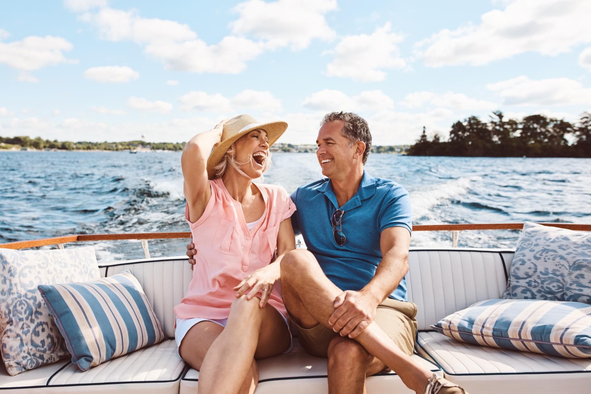 Couple laughing on a boat, enjoying a sunny day on the water.