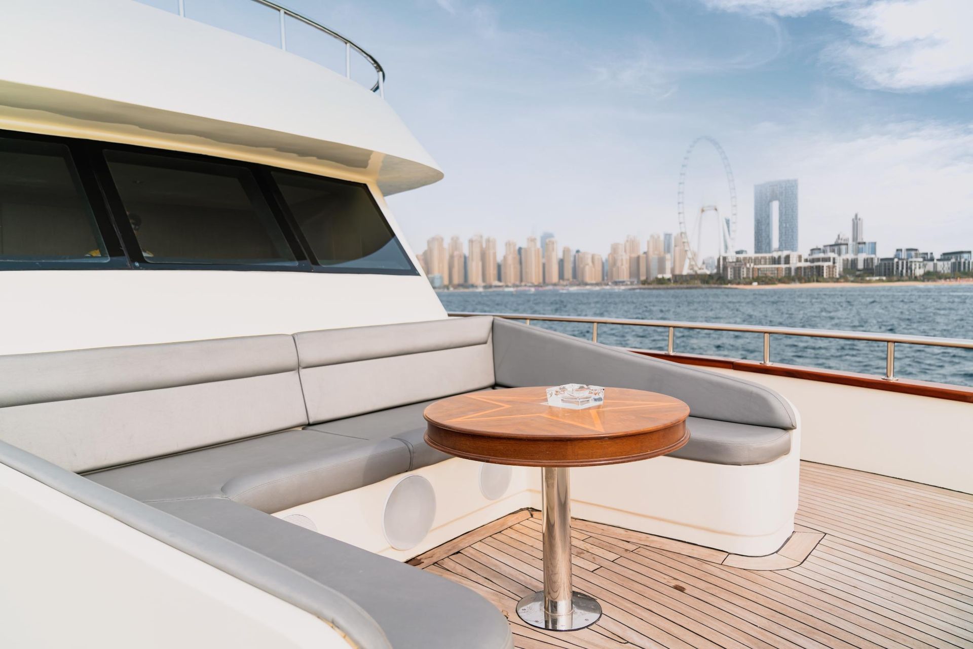 Yacht with seating area, round table, and city skyline view.