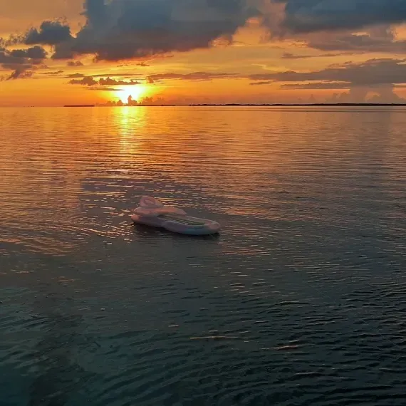 Sunset over water with a small boat, golden sky reflecting on the surface.
