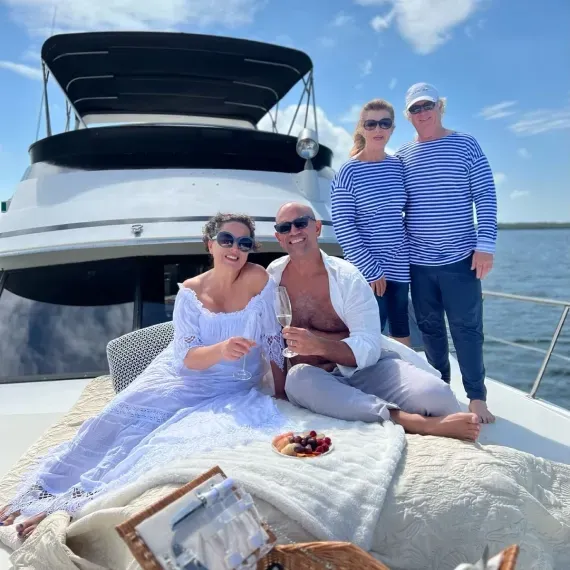 People relaxing on the bow of a boat on a sunny day; some sunbathe, read, and look at the ocean.