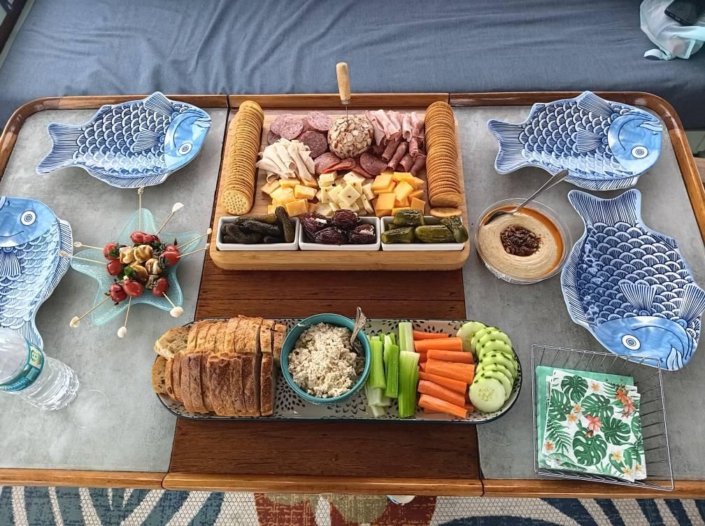Charcuterie board with meats, cheeses, crackers, and vegetables, plus fish-shaped plates.