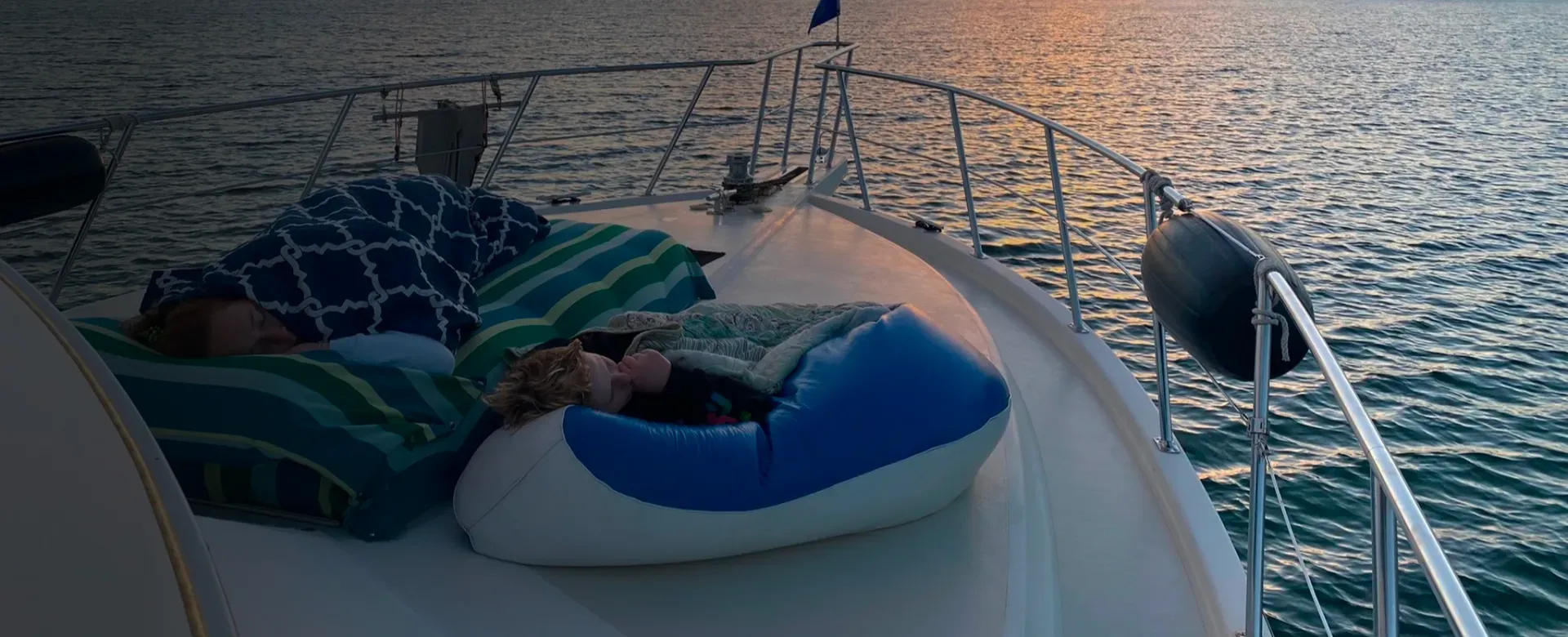 People sleeping on beanbags on a boat, with the sea in the background.
