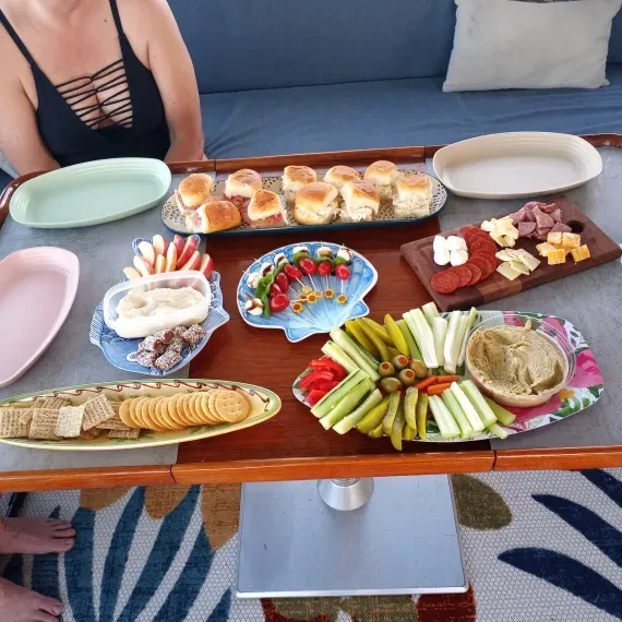 Charcuterie spread on a boat table; includes various snacks, cheeses, bread, and dips.