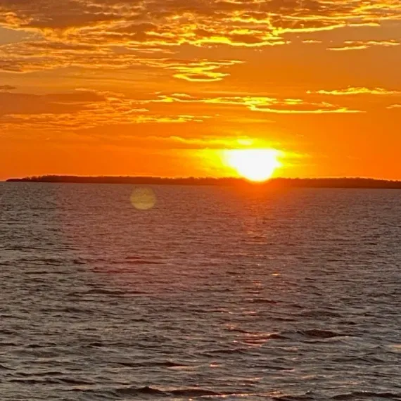 Four people sit around a table on a boat at night.