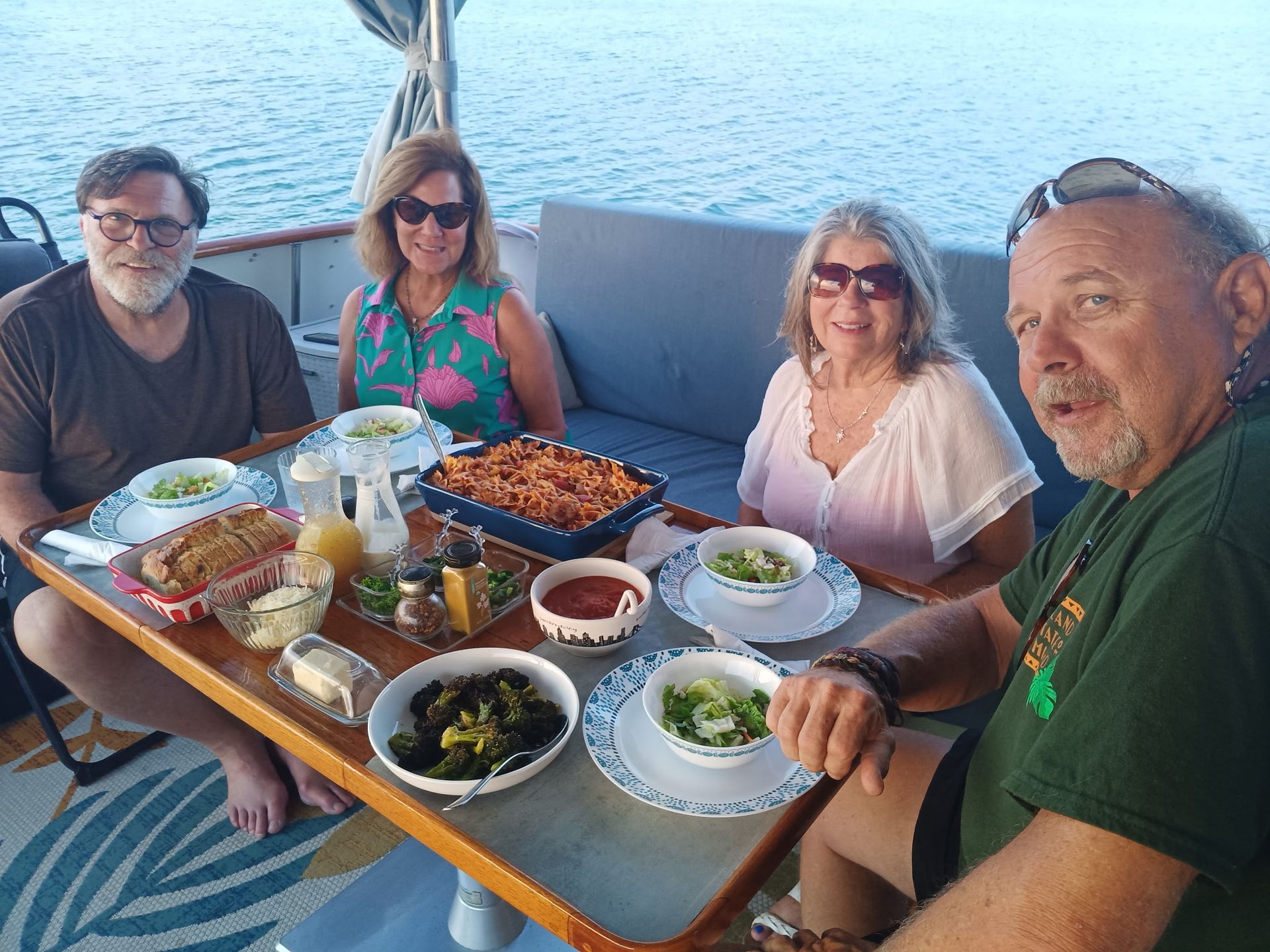 Four people seated at a table on a boat, enjoying a meal overlooking the water.