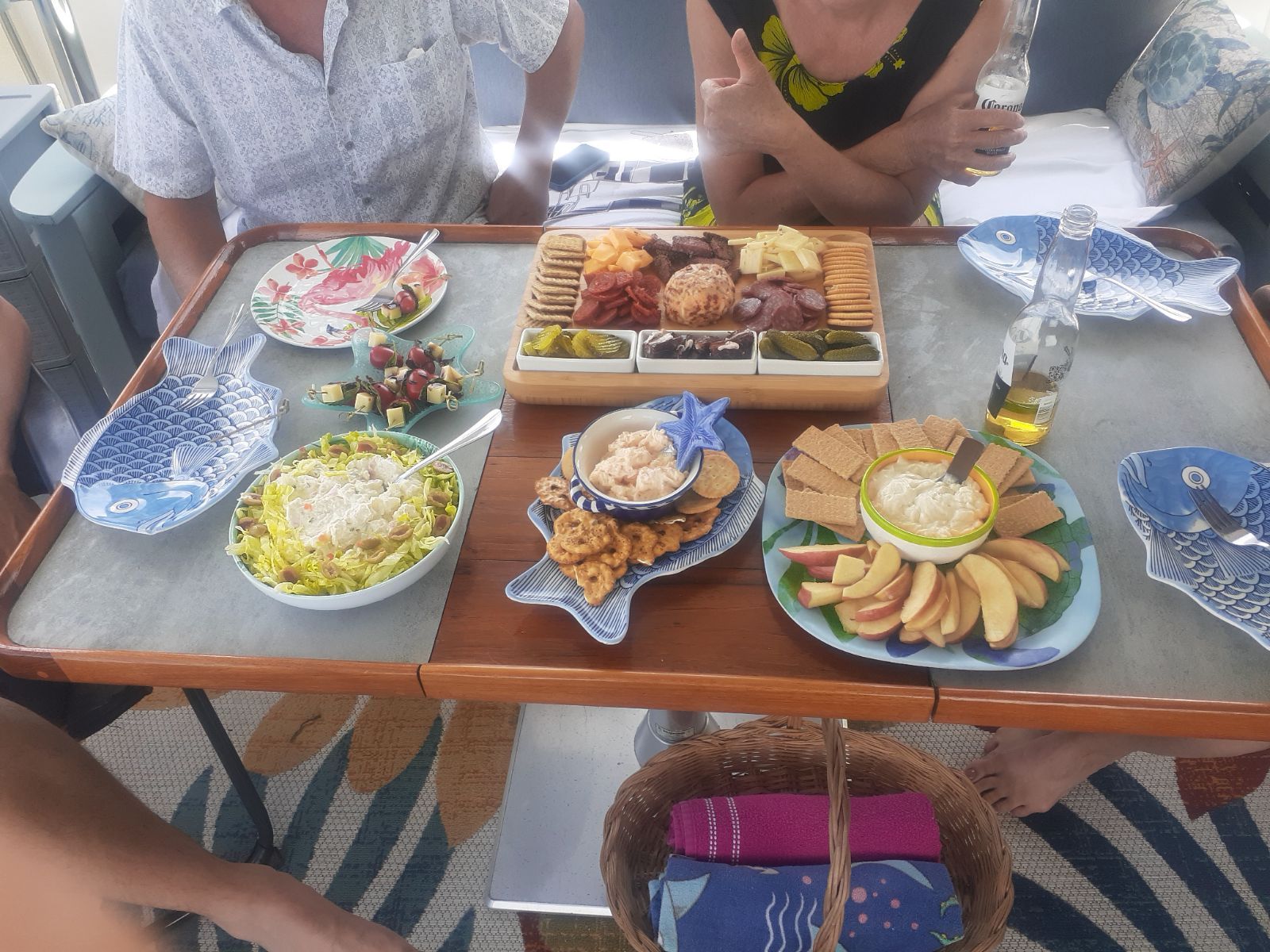 Table with charcuterie, dips, and sides on a boat; people are gathered around.