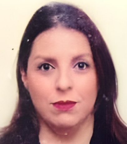 Woman with long brown hair, wearing a dark top, looking directly at the camera.