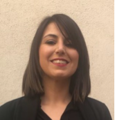 Woman with dark hair smiling, wearing a black sweater.