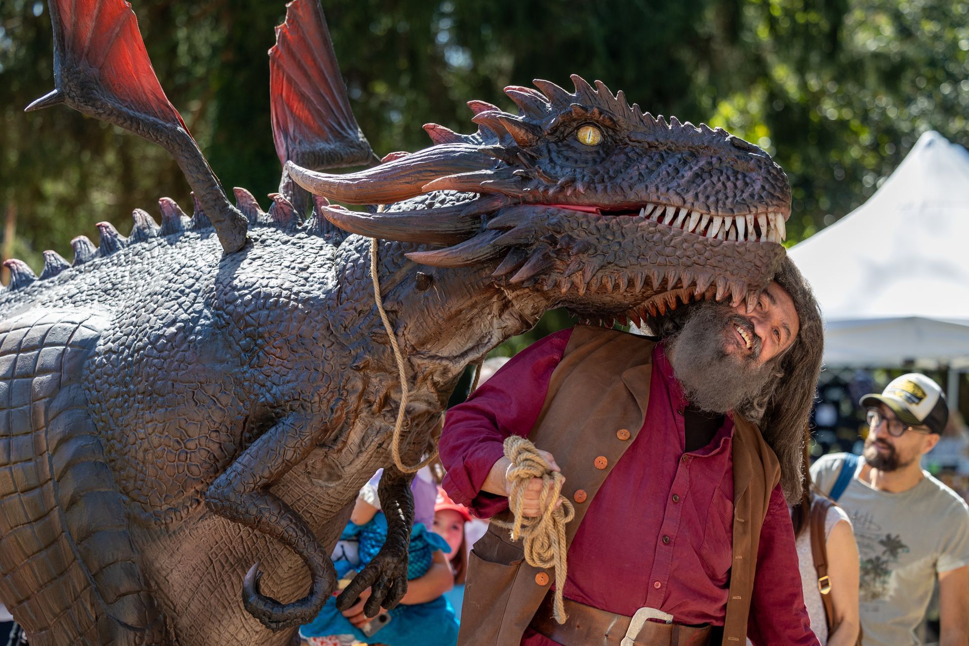 Il sosia del gigante Hagrid di Harry Potter in piedi accanto a un drago animatronico.