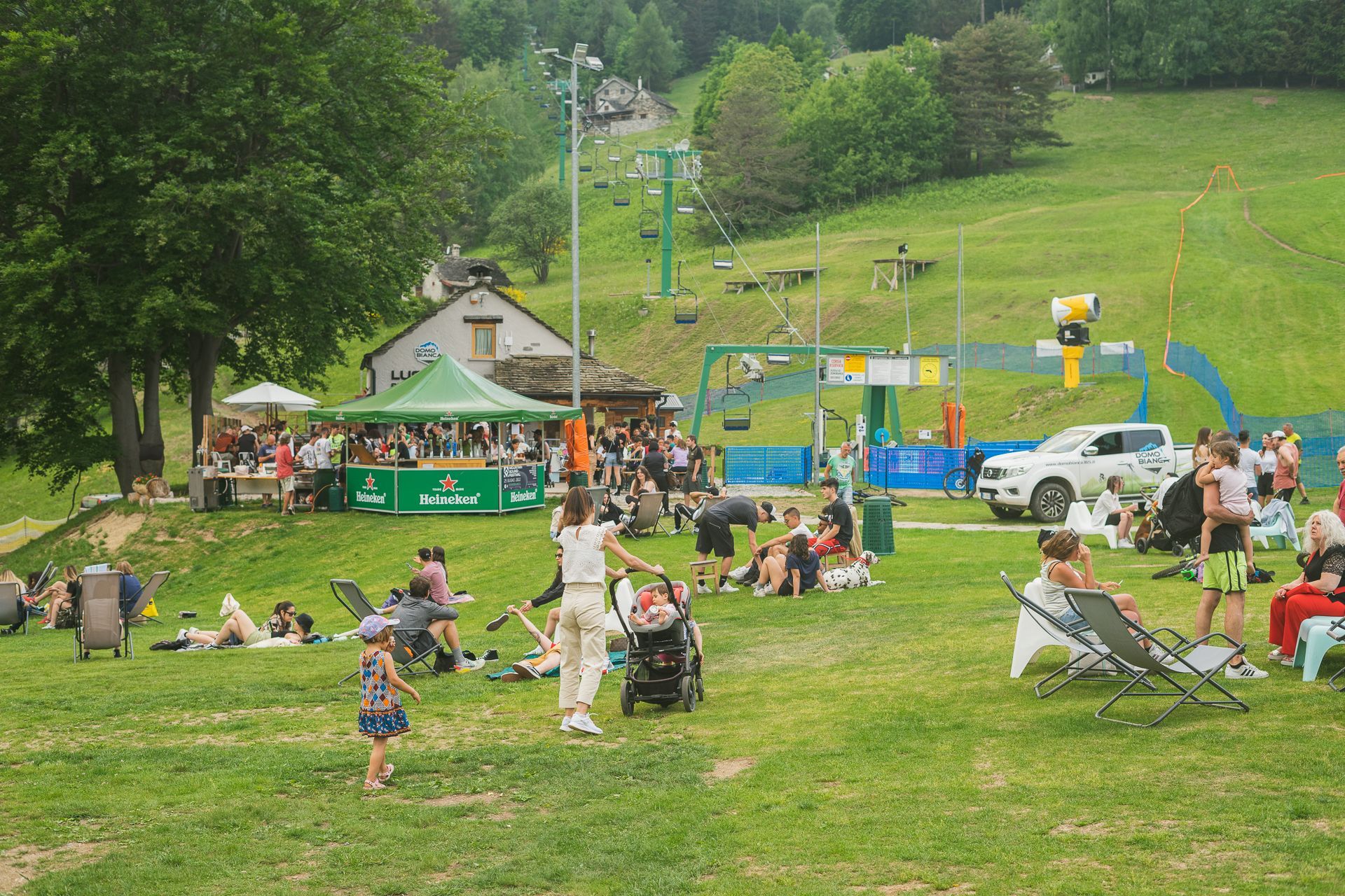 A group of people are having a picnic in a park with a ski lift in the background.