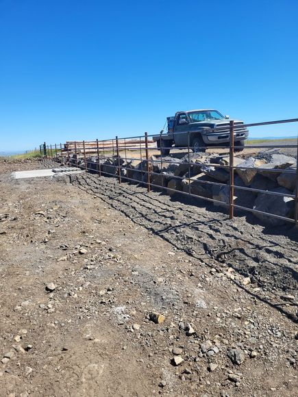 A truck is parked on the side of a dirt road next to a fence.