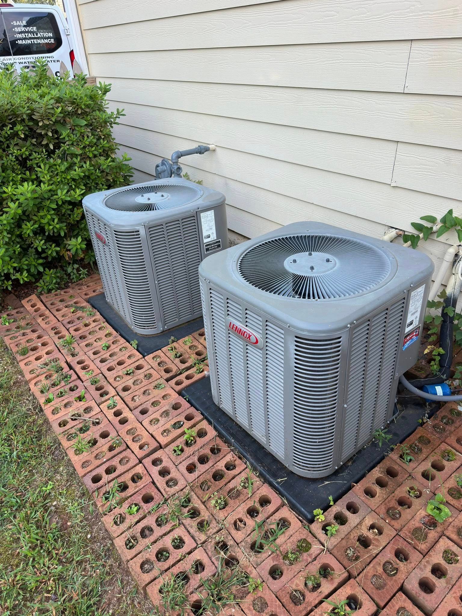 Two Goodman AC units on brick pavers next to a house.