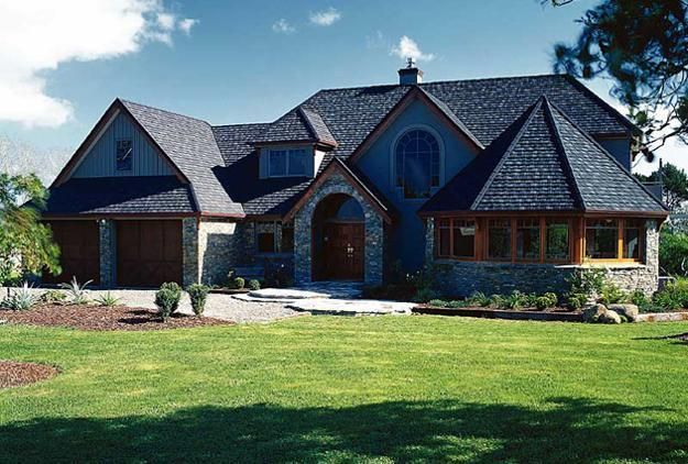 Large blue house with a stone facade, wooden accents, and a well-manicured lawn.