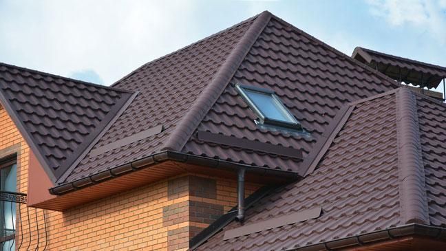 Brown metal roof on a brick house with a skylight.