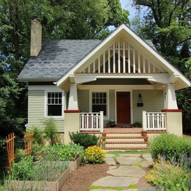 Small green house with porch, garden, and stone path.