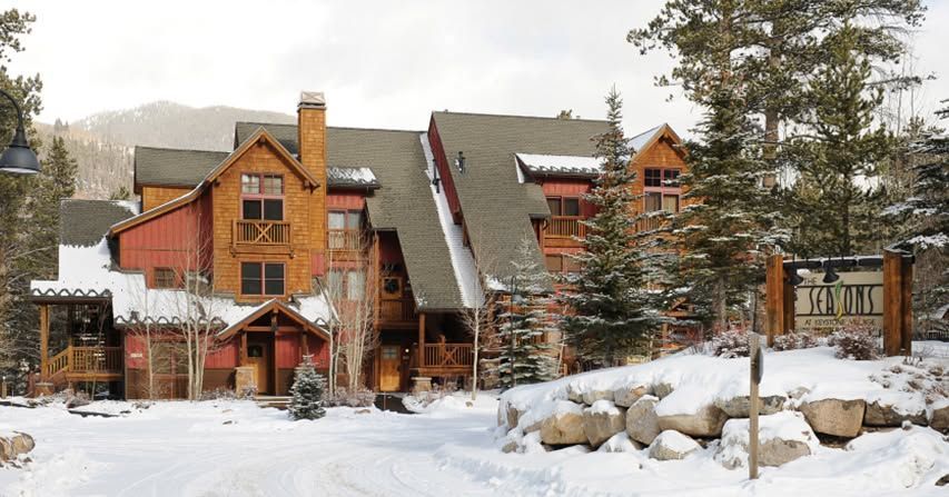 Snowy lodge with red siding and wooden accents; sign reads 