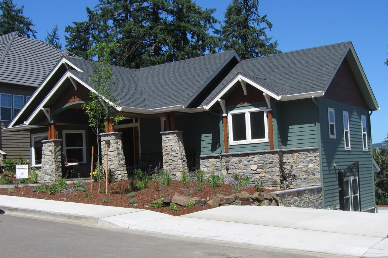 Green house with stone accents and a dark gray roof.