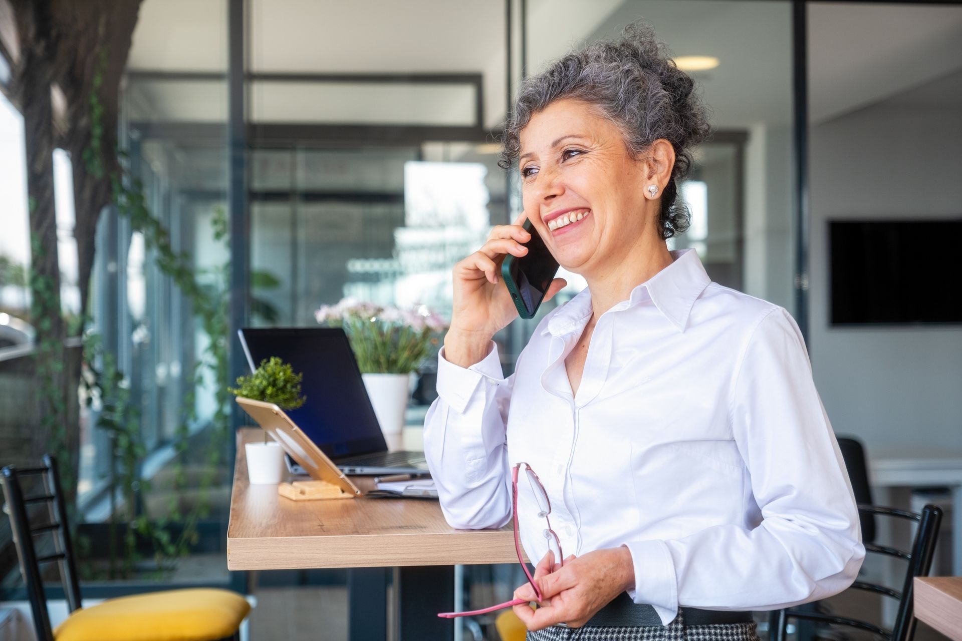 A woman is sitting at a table talking on a cell phone.