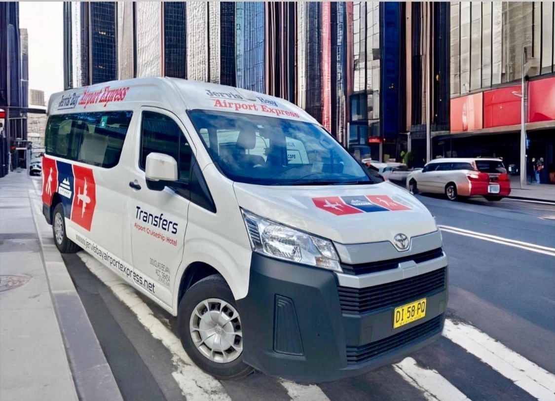 A White Van Is Parked On The Side Of The Road At An Airport — Jervis Bay Airport Express In Ulladulla, NSW