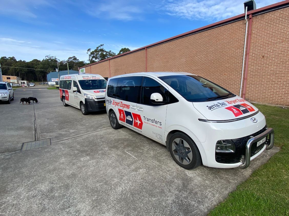 A Row Of White Vans Are Parked In A Parking Lot — Jervis Bay Airport Express In Albion Park, NSW