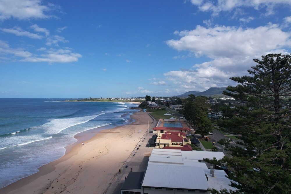 An Aerial View Of A Beach With Houses — Jervis Bay Airport Express In Thirroul, NSW