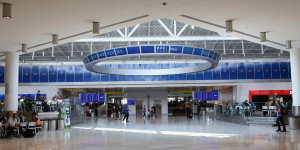A blurry picture of an airport terminal with a large circular sign hanging from the ceiling.