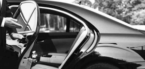 A man in a suit is opening the door of a car.