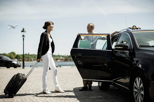 A woman with a suitcase is getting out of a car.
