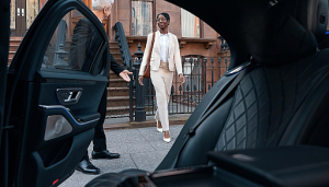 A man is welcoming a woman to get into a car.