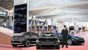 A man is standing in front of three cars in an airport.