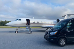 A private jet is parked next to a black van.