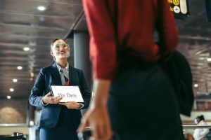 A woman in a suit is talking to a woman in a red shirt at an airport.