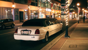 A white limousine is parked on the side of a city street at night.