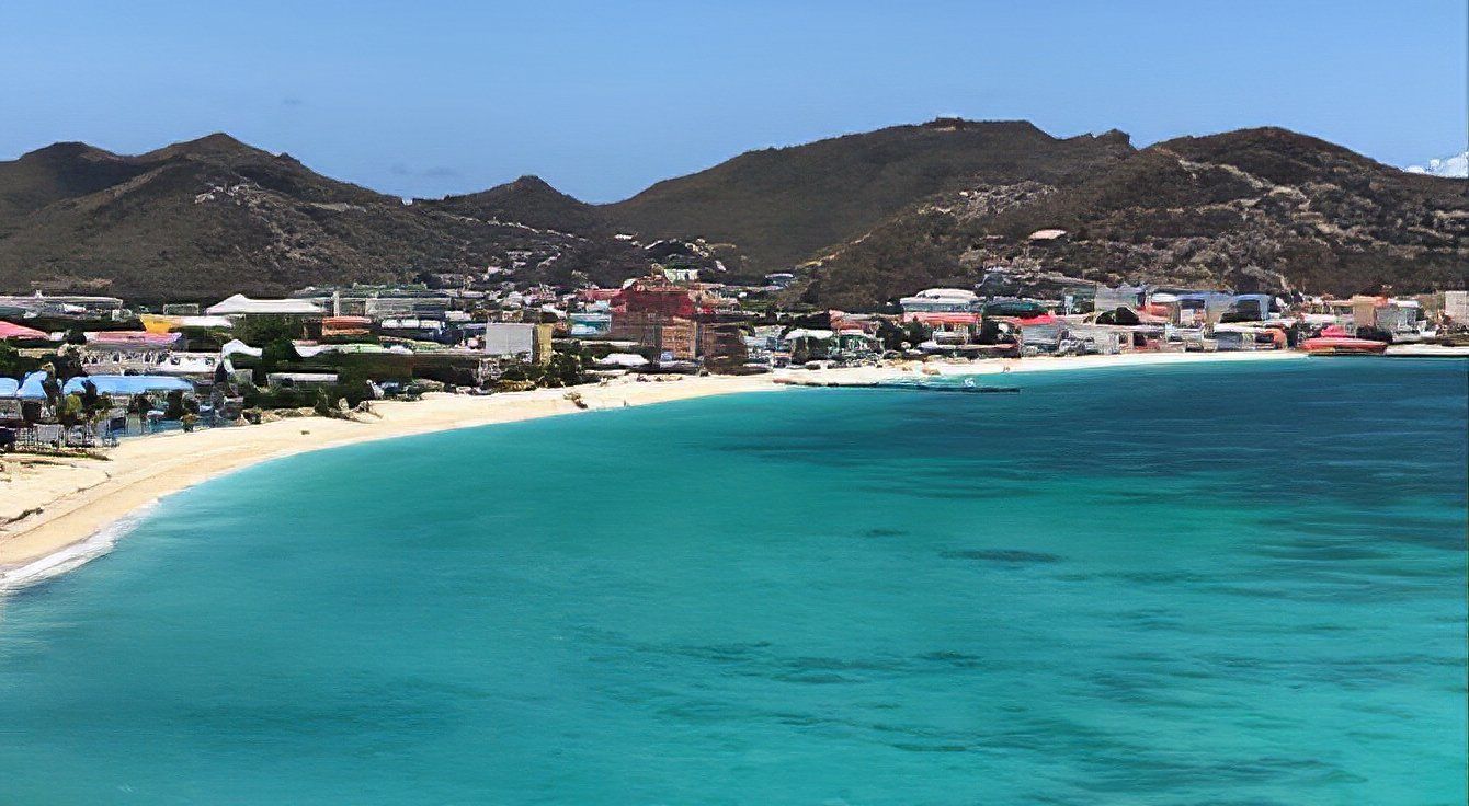 A beach with mountains in the background and a city in the distance.