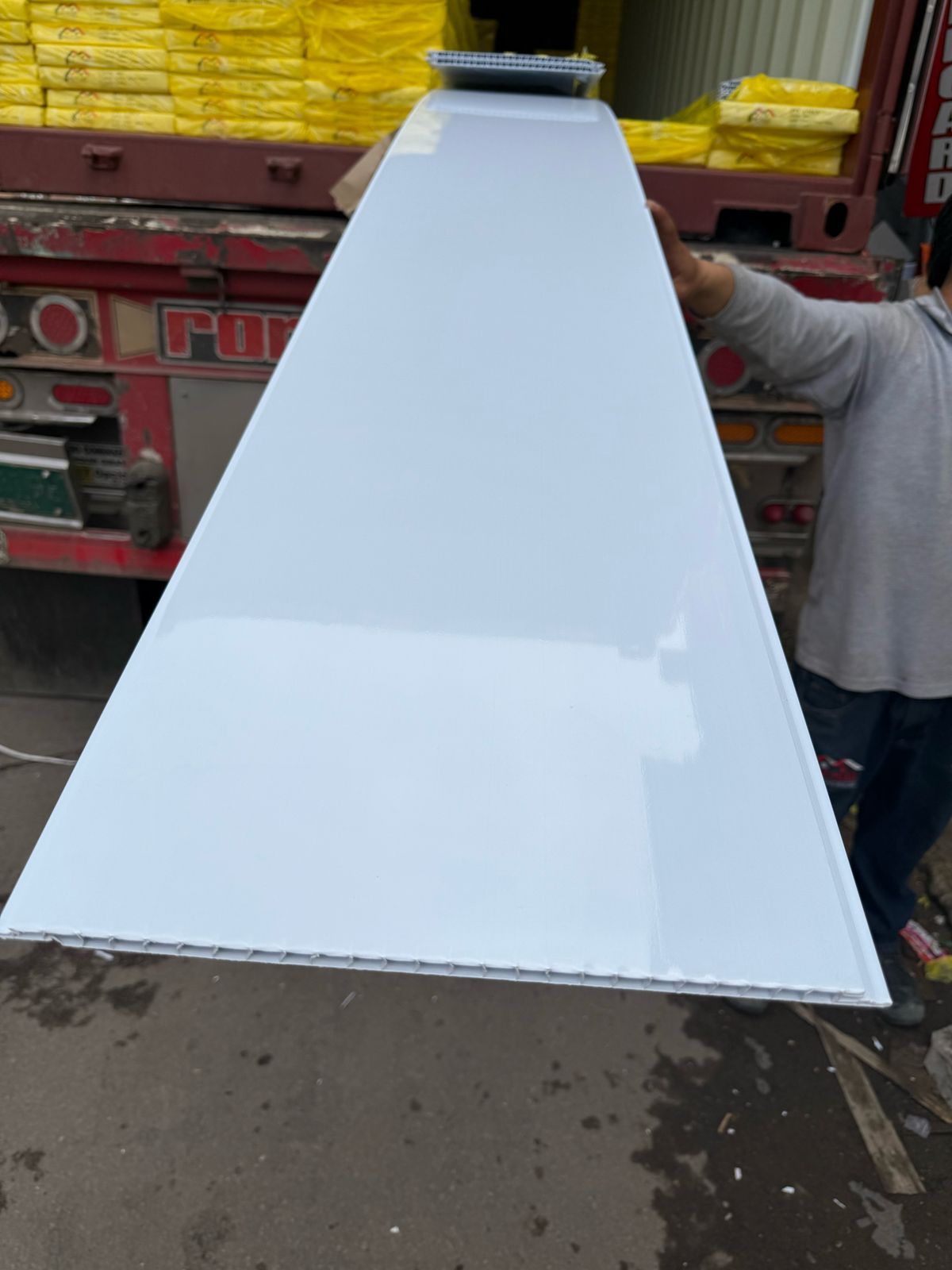 Un hombre sostiene un trozo largo de plástico blanco.