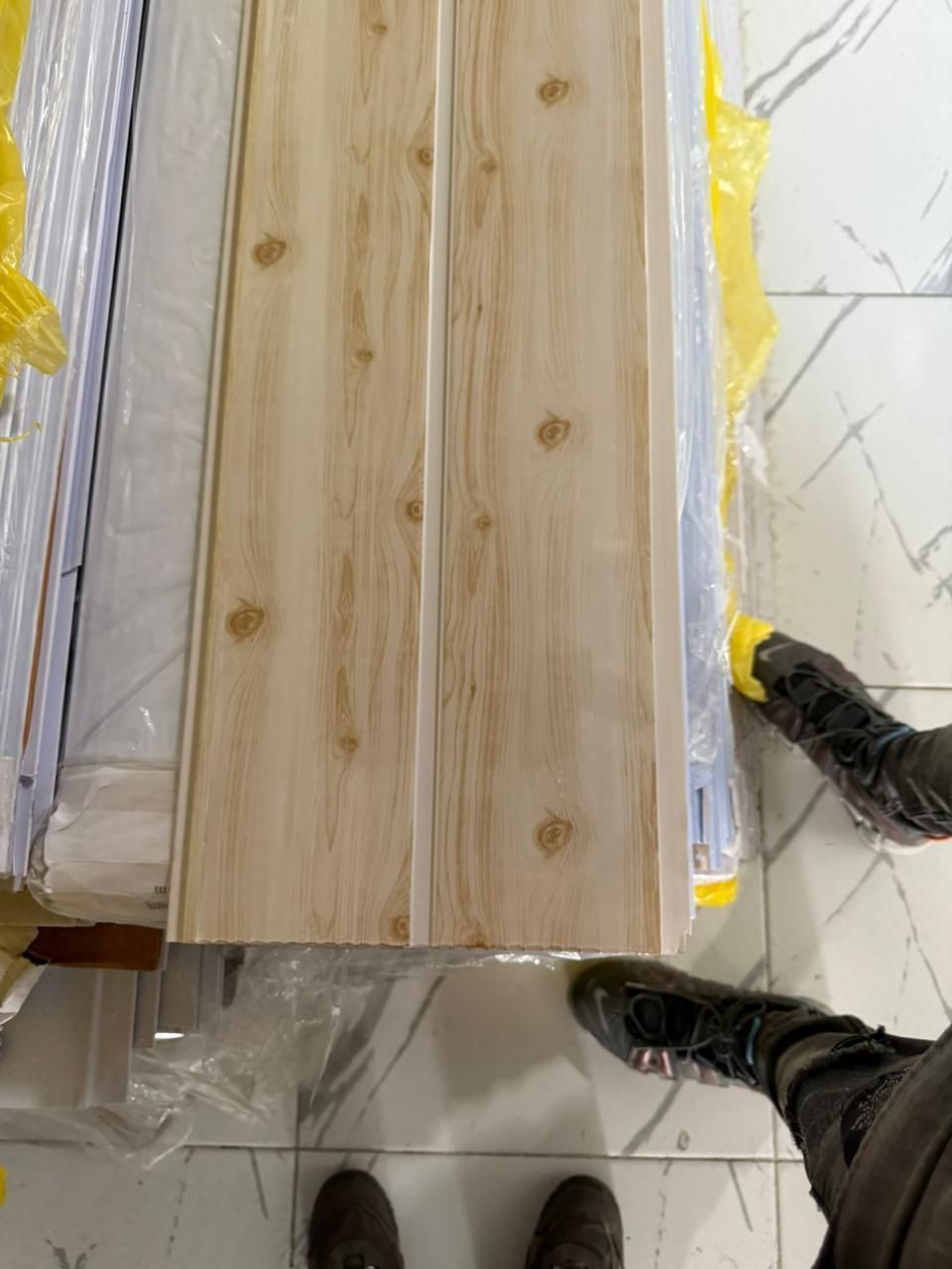 Una persona está de pie junto a una pila de paneles de madera.