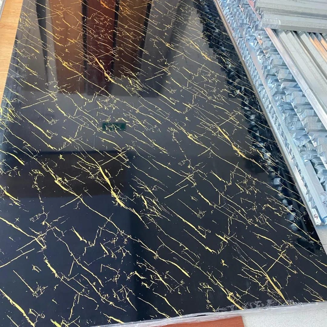 Un azulejo negro y dorado con un patrón de mármol está sobre una mesa.