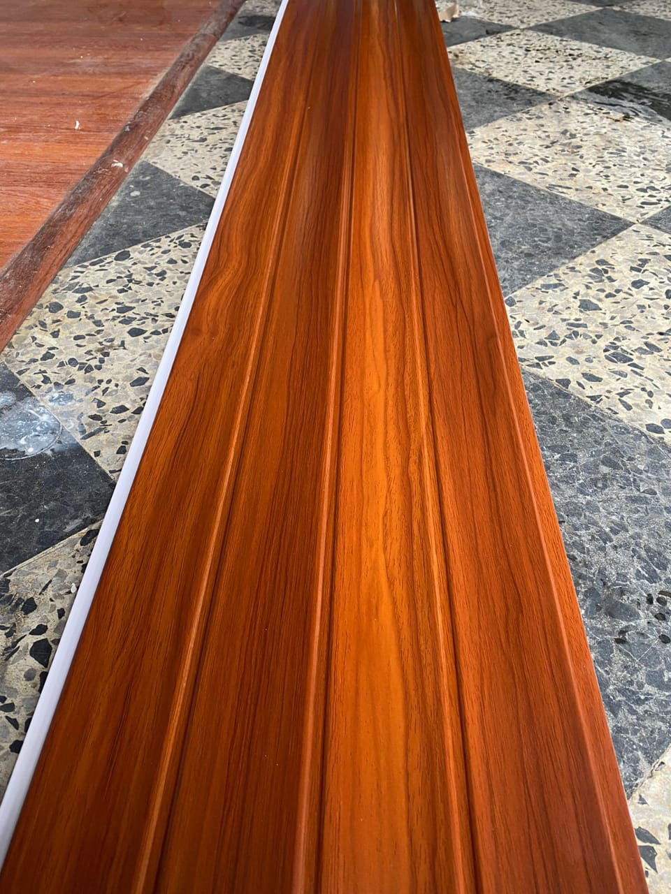 Un trozo de madera reposa sobre un suelo cuadriculado.