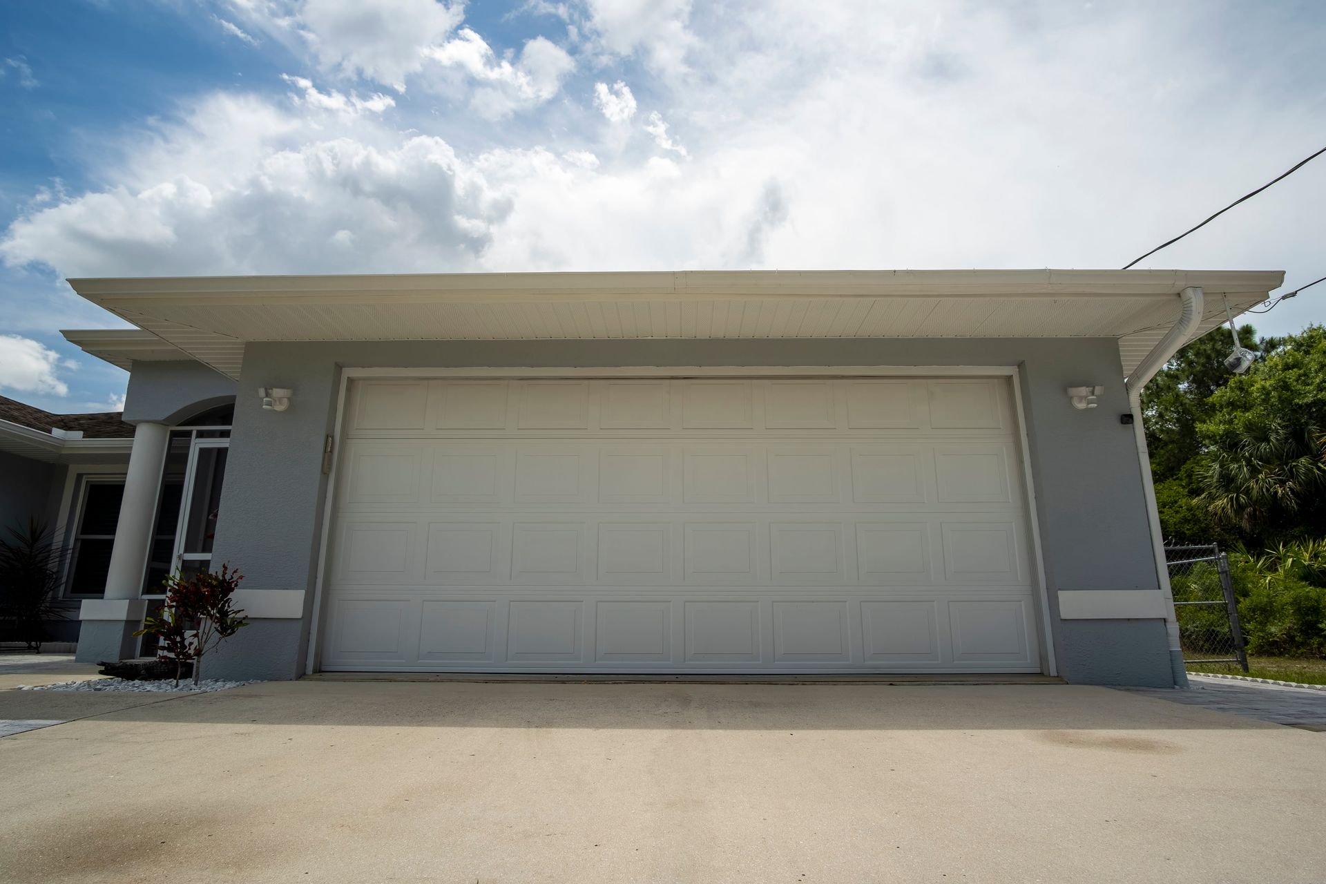 Gray garage with white door and roof, against a cloudy sky.