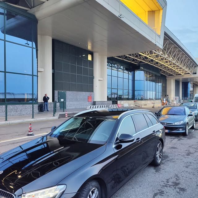 Un'auto nera è parcheggiata davanti a un grande edificio