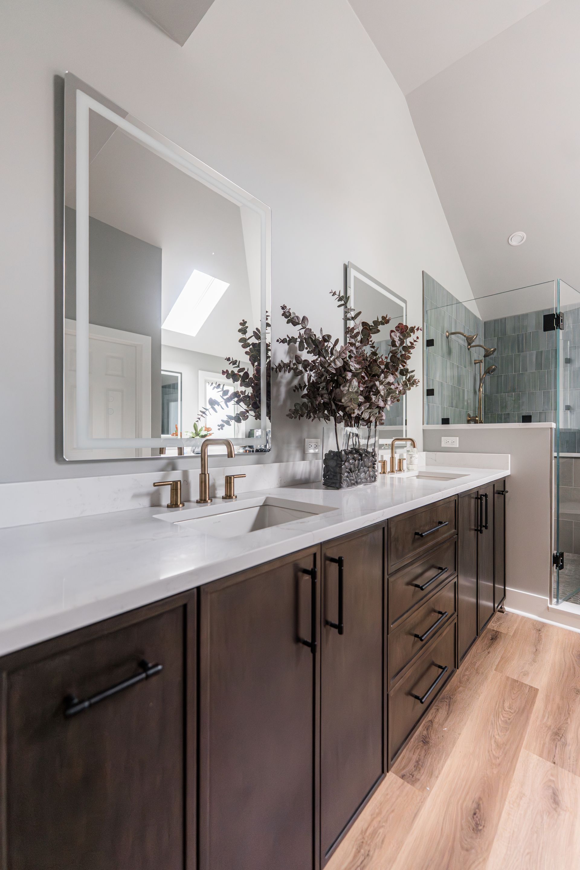 Modern bathroom with dark wood vanity, white countertop, mirror, and glass shower enclosure