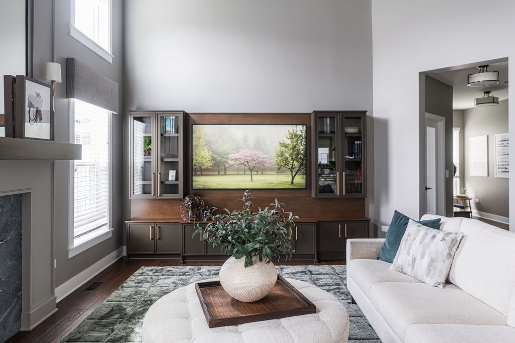Modern living room with white sofas, TV, large mirror, and soft gray decor