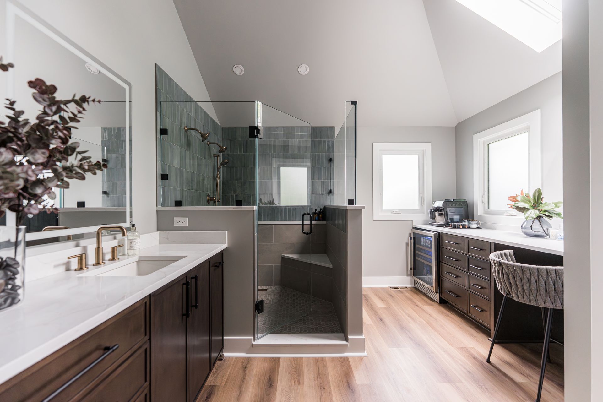 Bright modern bathroom with glass shower, double vanity, and a freestanding tub by a window.
