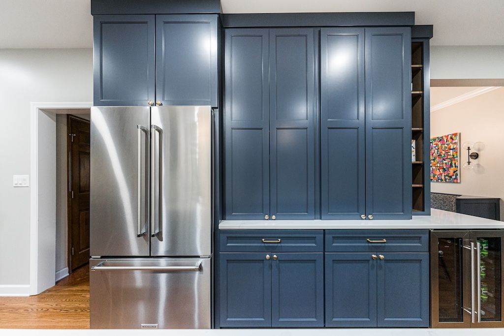 Stainless steel refrigerator and navy blue kitchen cabinets.