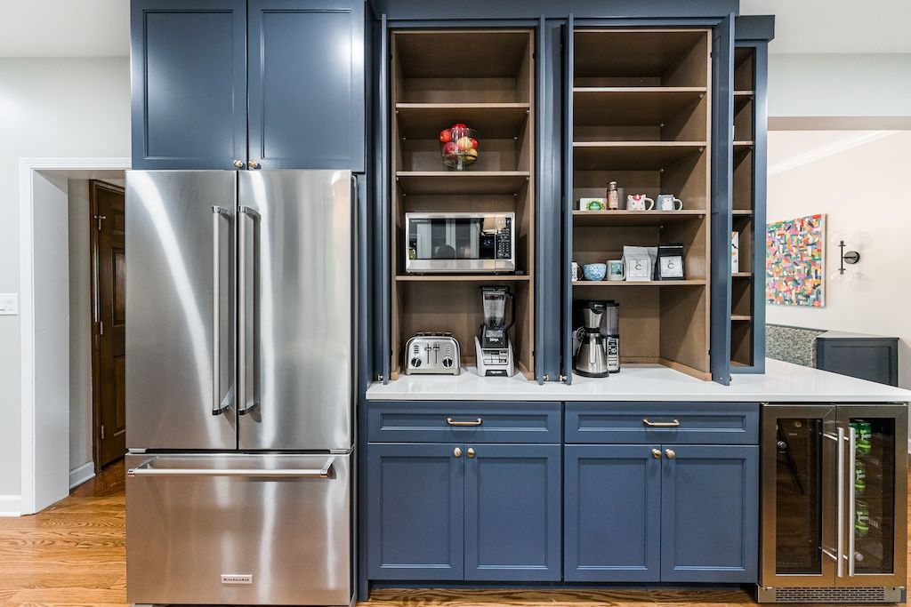 Blue kitchen cabinetry with refrigerator and built-in coffee station, including appliances and a small wine cooler.